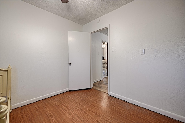 empty room with ceiling fan, hardwood / wood-style floors, and a textured ceiling