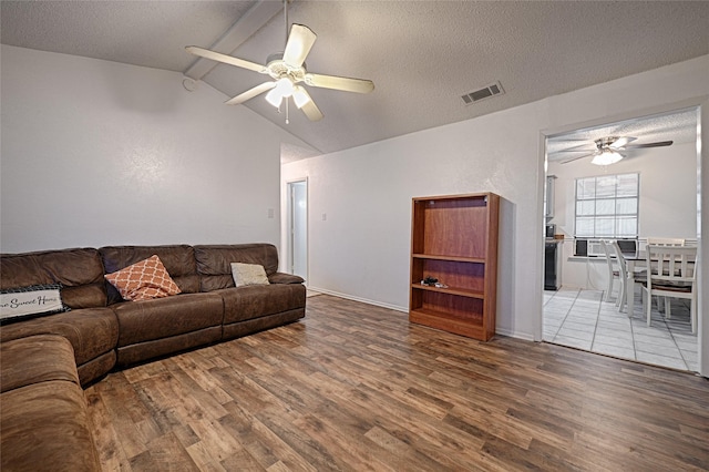 living room featuring hardwood / wood-style floors, a textured ceiling, ceiling fan, and lofted ceiling