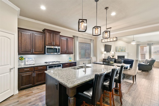 kitchen with sink, a kitchen bar, dark brown cabinetry, stainless steel appliances, and a center island with sink