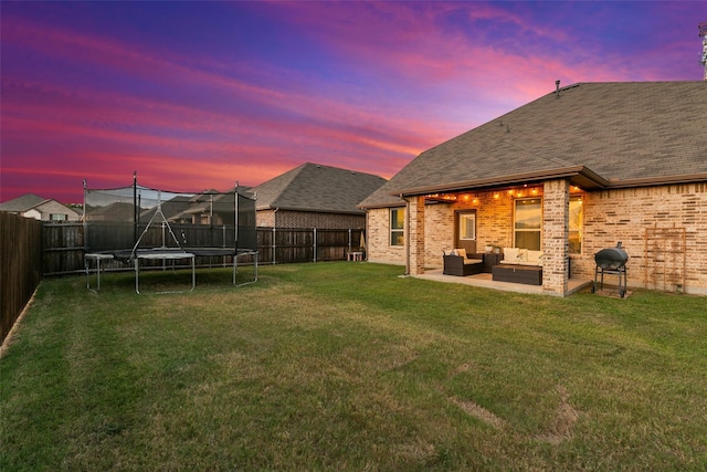 yard at dusk featuring an outdoor hangout area, a patio area, and a trampoline