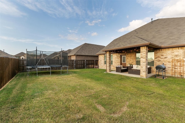 view of yard with a trampoline, a patio, and an outdoor living space with a fireplace