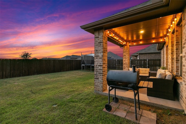 yard at dusk with outdoor lounge area and a trampoline