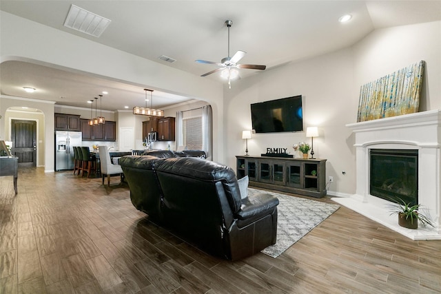 living room featuring crown molding, ceiling fan, wood-type flooring, and vaulted ceiling