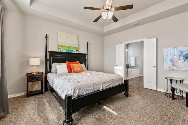 carpeted bedroom with ceiling fan, ensuite bathroom, and a tray ceiling