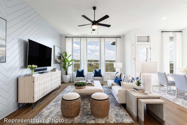 living room featuring dark hardwood / wood-style floors, wood walls, and ceiling fan