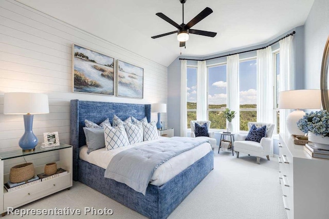 bedroom featuring ceiling fan, wooden walls, light carpet, and lofted ceiling