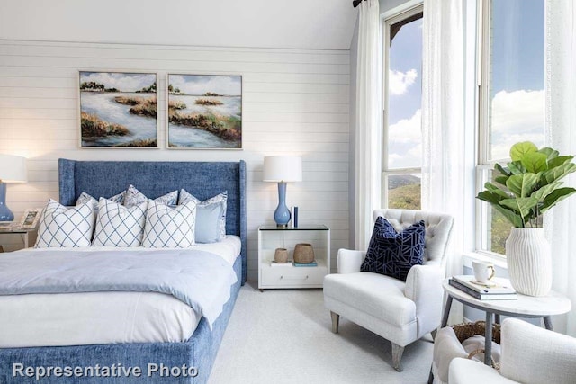 carpeted bedroom featuring wood walls