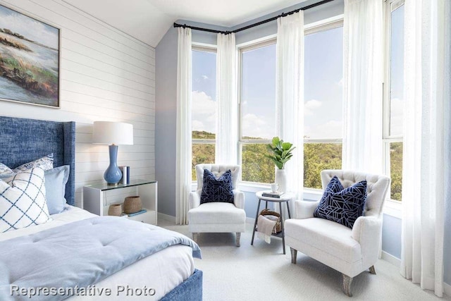 carpeted bedroom featuring multiple windows, wood walls, and vaulted ceiling