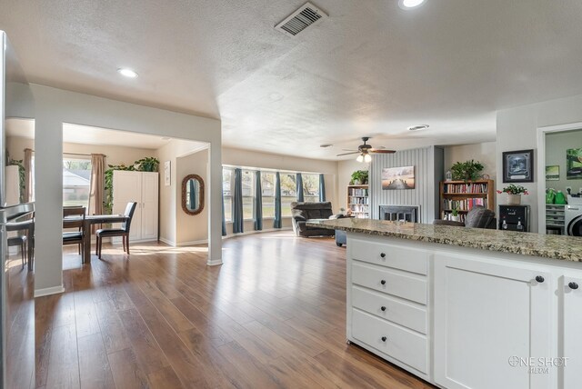 kitchen featuring white cabinets, light hardwood / wood-style floors, light stone counters, and a wealth of natural light