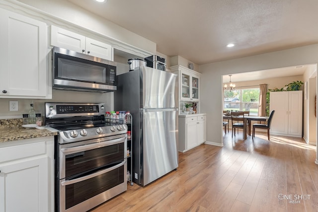 kitchen with light stone counters, light hardwood / wood-style flooring, white cabinets, and stainless steel appliances