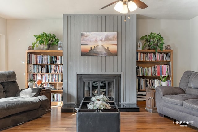 sitting room featuring ceiling fan, a fireplace, and wood-type flooring