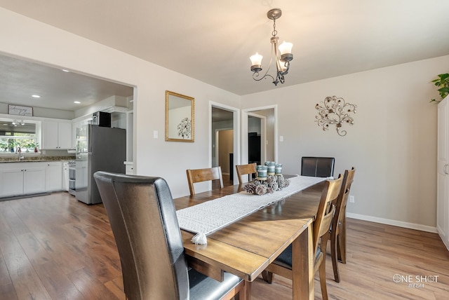 dining area with light hardwood / wood-style flooring, a notable chandelier, and sink