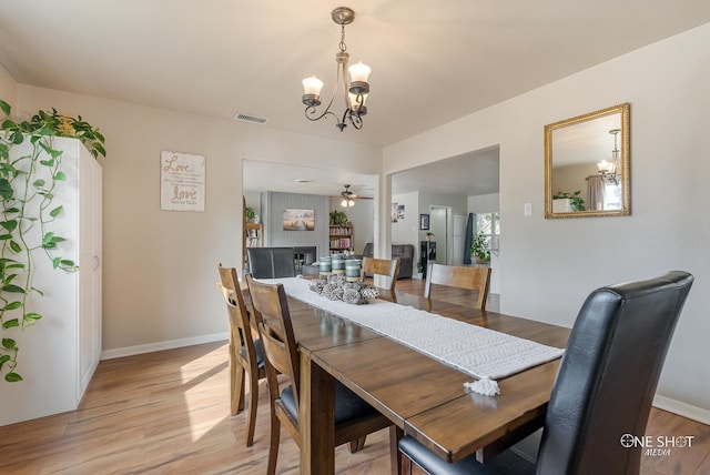 dining space featuring ceiling fan with notable chandelier and light hardwood / wood-style floors