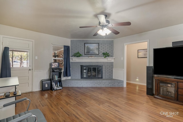 living room featuring ceiling fan, a fireplace, and wood-type flooring