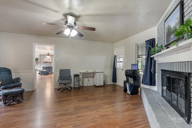 office space featuring hardwood / wood-style floors, ceiling fan, and a brick fireplace