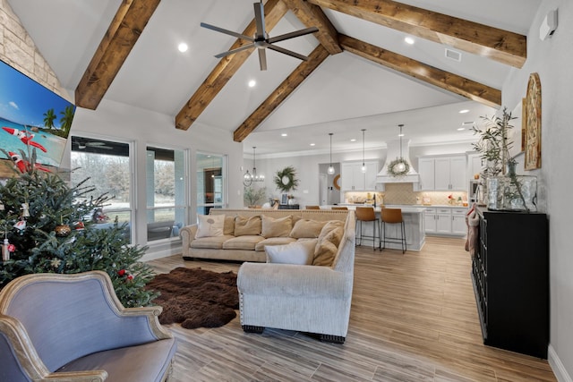 living room with ceiling fan with notable chandelier, beam ceiling, and high vaulted ceiling