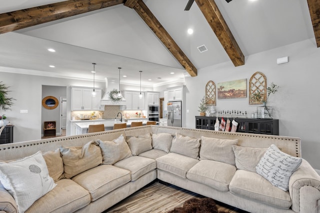 living room with lofted ceiling with beams, ornamental molding, and sink