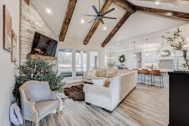 living room featuring beamed ceiling, light wood-type flooring, ceiling fan with notable chandelier, and high vaulted ceiling