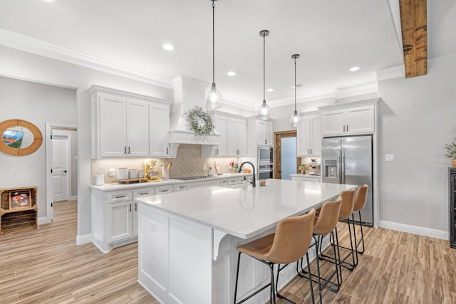 kitchen featuring white cabinetry, a center island with sink, decorative light fixtures, and appliances with stainless steel finishes