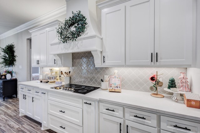 kitchen featuring backsplash, ornamental molding, custom exhaust hood, black electric cooktop, and white cabinetry