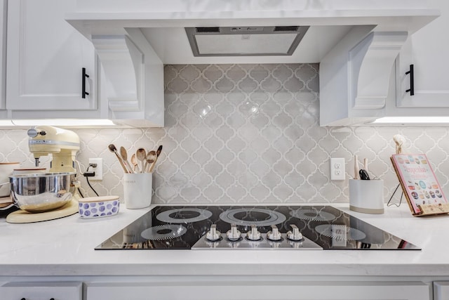 kitchen featuring backsplash, black electric stovetop, white cabinets, and custom exhaust hood