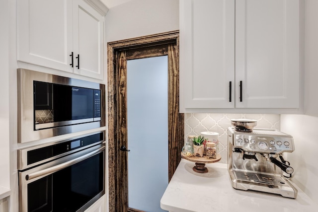 kitchen with white cabinets, decorative backsplash, stainless steel oven, and built in microwave