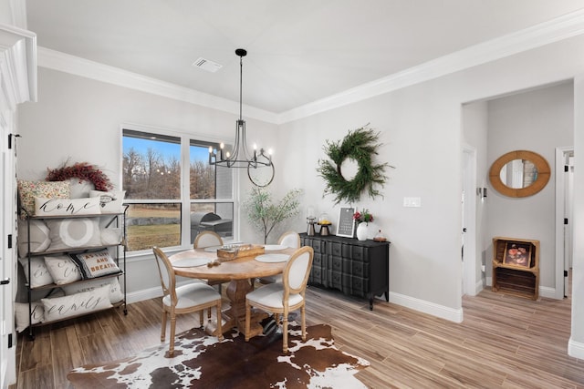 dining room with crown molding, light hardwood / wood-style flooring, and a notable chandelier