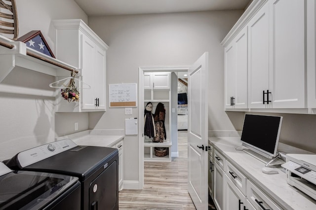 laundry area with washer and clothes dryer, cabinets, and light wood-type flooring