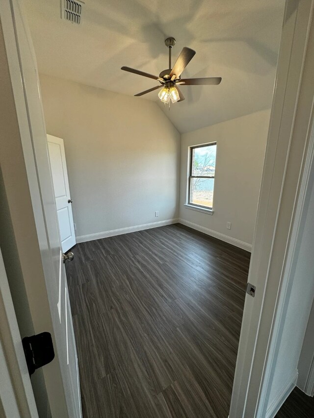 empty room with dark hardwood / wood-style floors, ceiling fan, and vaulted ceiling