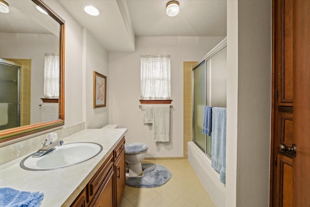 full bathroom featuring combined bath / shower with glass door, vanity, and toilet