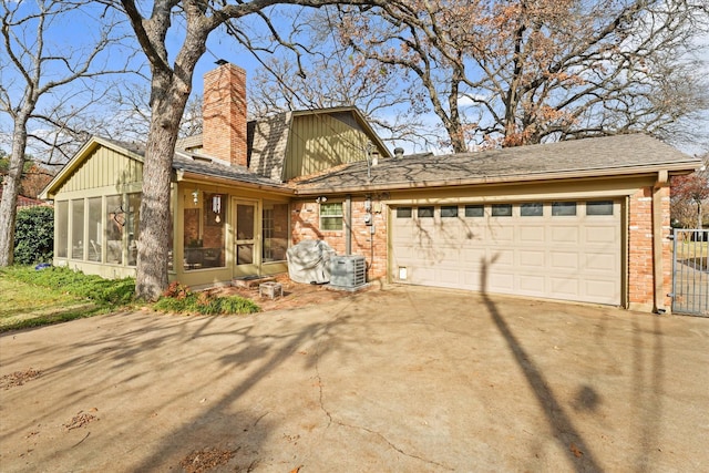 view of front of home with central air condition unit, a garage, and a sunroom