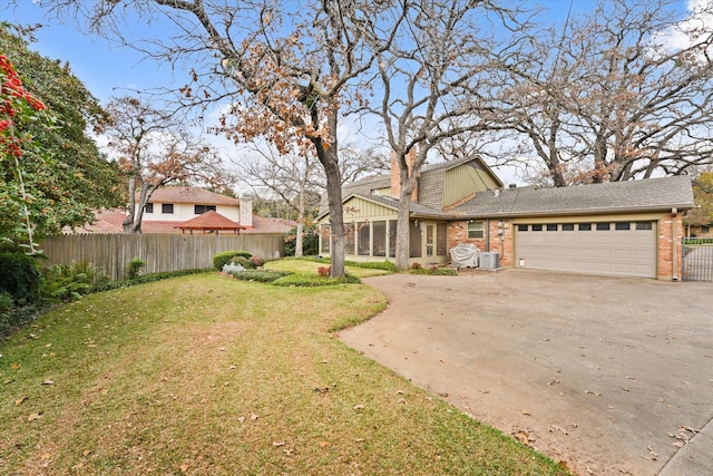 view of front of house featuring central AC, a garage, a front lawn, and a sunroom