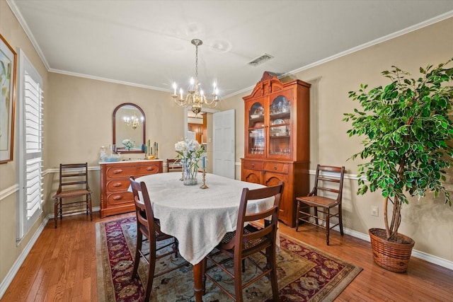 dining room with hardwood / wood-style flooring, an inviting chandelier, and crown molding