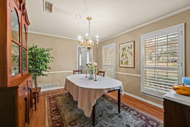 dining room with a wealth of natural light, crown molding, a notable chandelier, and hardwood / wood-style flooring