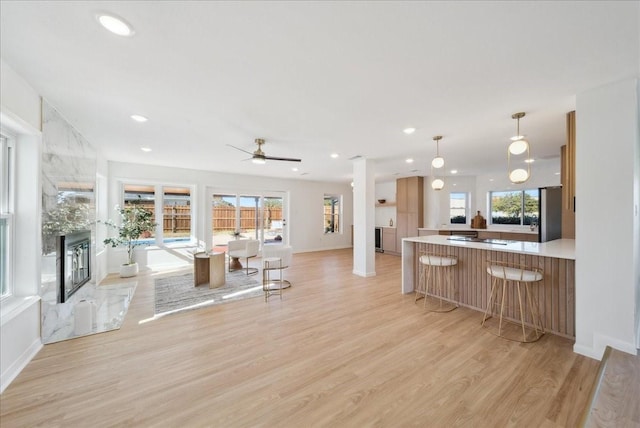 kitchen featuring kitchen peninsula, ceiling fan, a healthy amount of sunlight, and light hardwood / wood-style floors