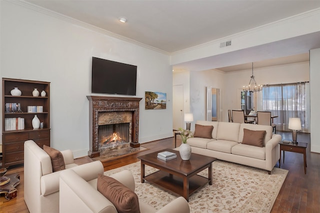 living room featuring an inviting chandelier, a high end fireplace, crown molding, and hardwood / wood-style flooring