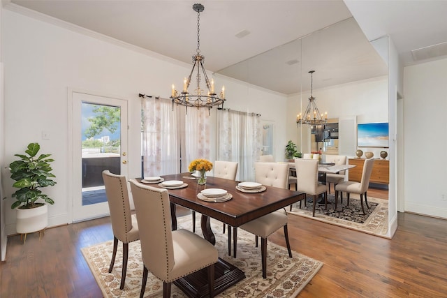 dining area with crown molding, dark hardwood / wood-style floors, and an inviting chandelier