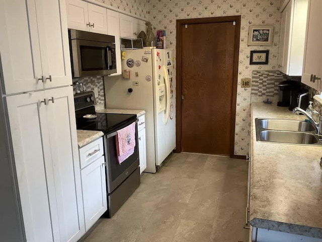 kitchen featuring backsplash, sink, white cabinets, and stainless steel range with electric stovetop