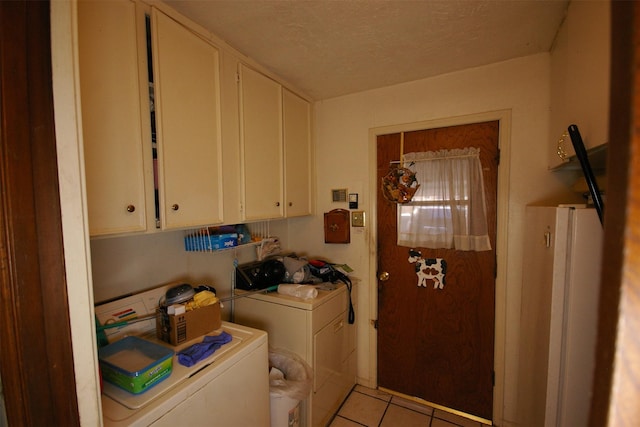 laundry area featuring cabinets, light tile patterned floors, and washer and clothes dryer