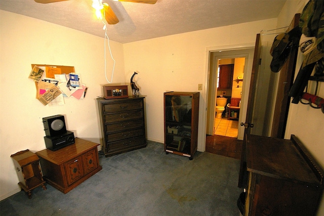 misc room featuring dark colored carpet, a textured ceiling, and ceiling fan