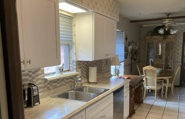 kitchen featuring sink, white cabinets, stainless steel dishwasher, backsplash, and light tile patterned flooring