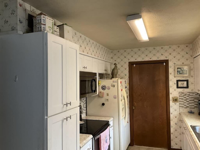 kitchen featuring range with electric stovetop, white cabinetry, white refrigerator with ice dispenser, and white refrigerator