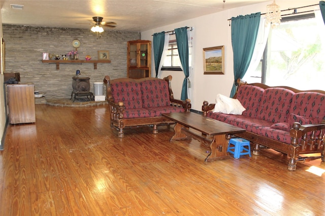 living room featuring a wood stove, hardwood / wood-style floors, and ceiling fan