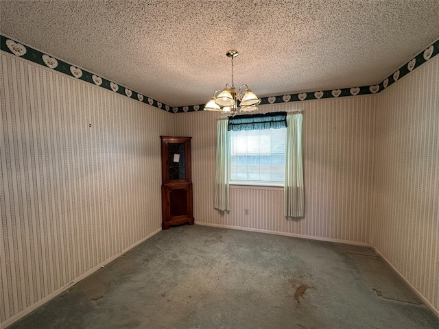 spare room with carpet floors, a textured ceiling, and an inviting chandelier