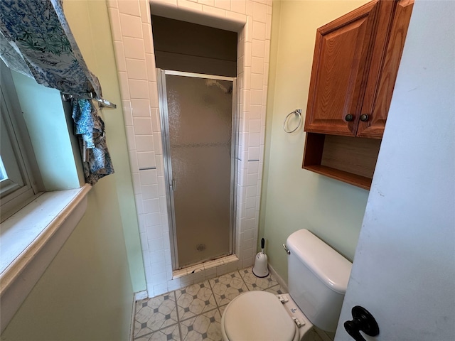 bathroom with tile patterned flooring, a shower with shower door, and toilet