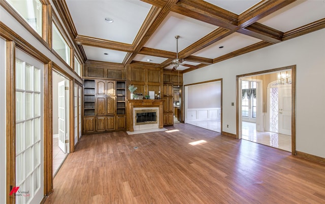 unfurnished living room with beam ceiling, ceiling fan with notable chandelier, coffered ceiling, and light wood-type flooring