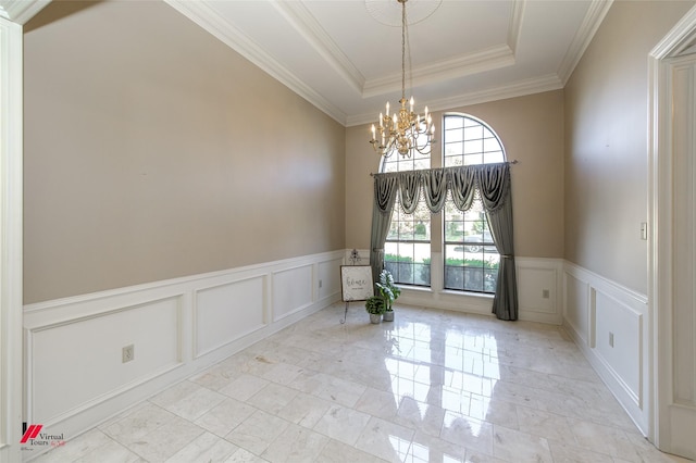 empty room featuring a tray ceiling, ornamental molding, and a notable chandelier