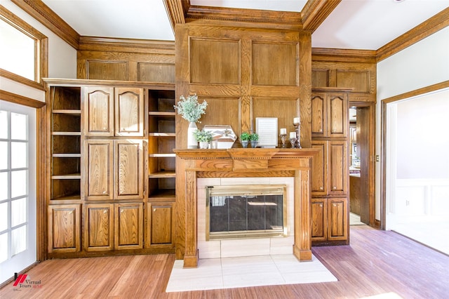 unfurnished living room featuring crown molding, a fireplace with flush hearth, and light wood-style floors