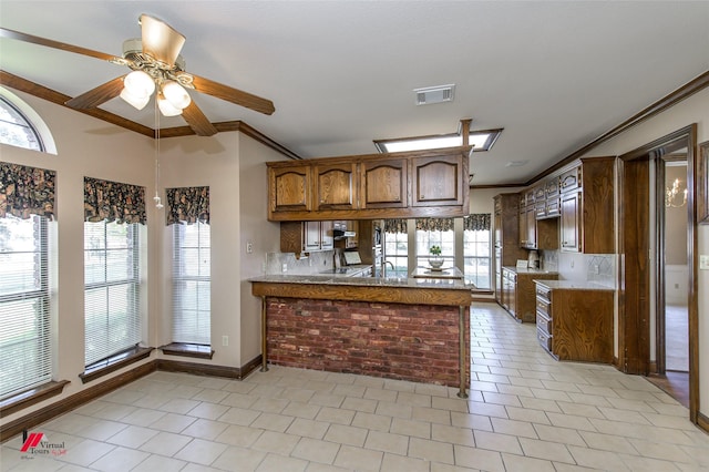 kitchen with kitchen peninsula, light tile patterned floors, ceiling fan, and crown molding