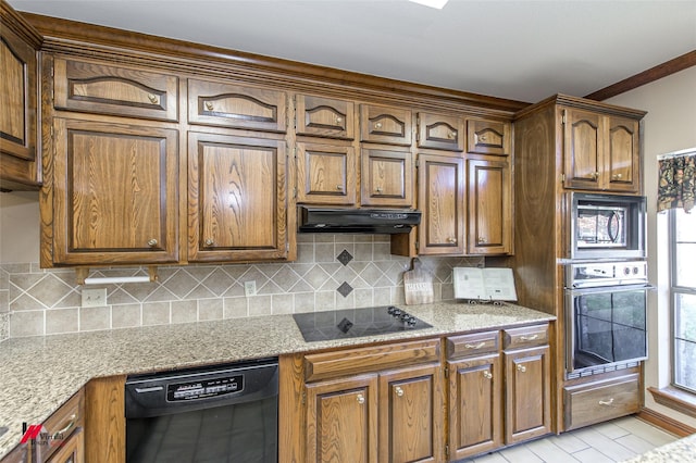 kitchen with black appliances, light stone counters, and backsplash